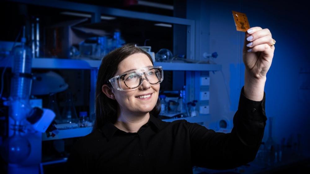 Jessie Posar is looking up at a printed x-ray scanner in a blue lab