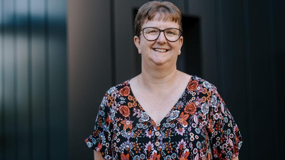 A women stands outside a building and smiles. Photo: Michael Gray