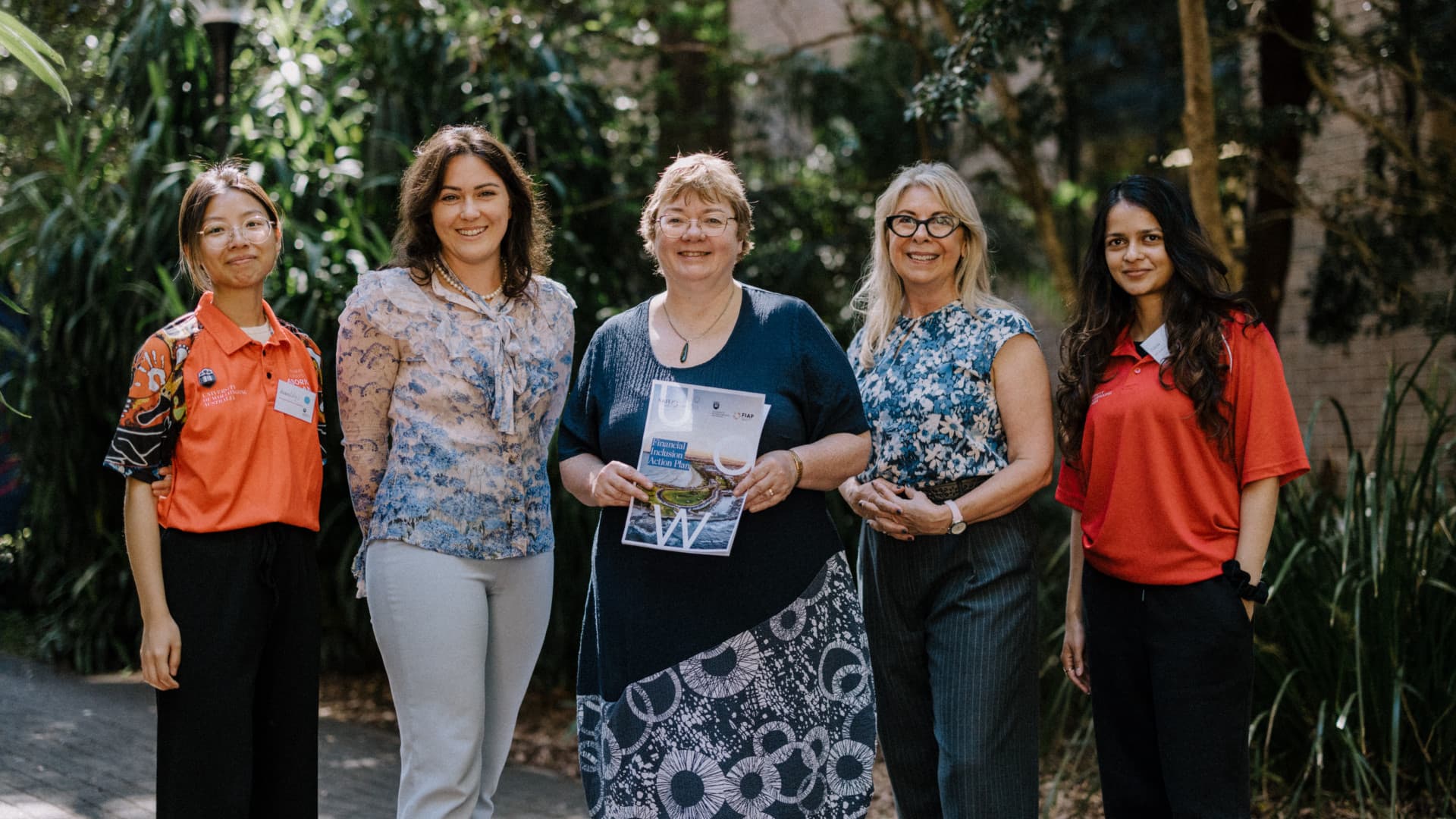 Two students in red shirts flank Anne Barrow, Eileen McLaughlin and Roslyn Russell as they hold the Financial Inclusion Action Plan. Photo: Michael Gray