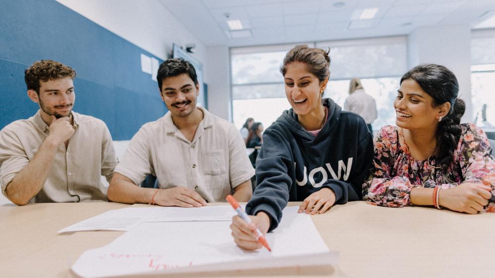 Four students work at a desk during the Financial Inclusion Action Plan workshop. Photo: Michael Gray