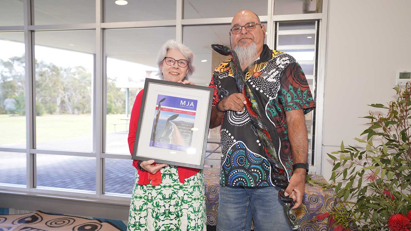 Professor Virginia Barbour Editor-in-Chief Medical Journal of Australia and Uncle Paul Scott handing over the Red Belly Snake Walking Stick at the Medical Journal of Australia hosted First Nations Cultural Sharing Gathering at UOW Shoalhaven