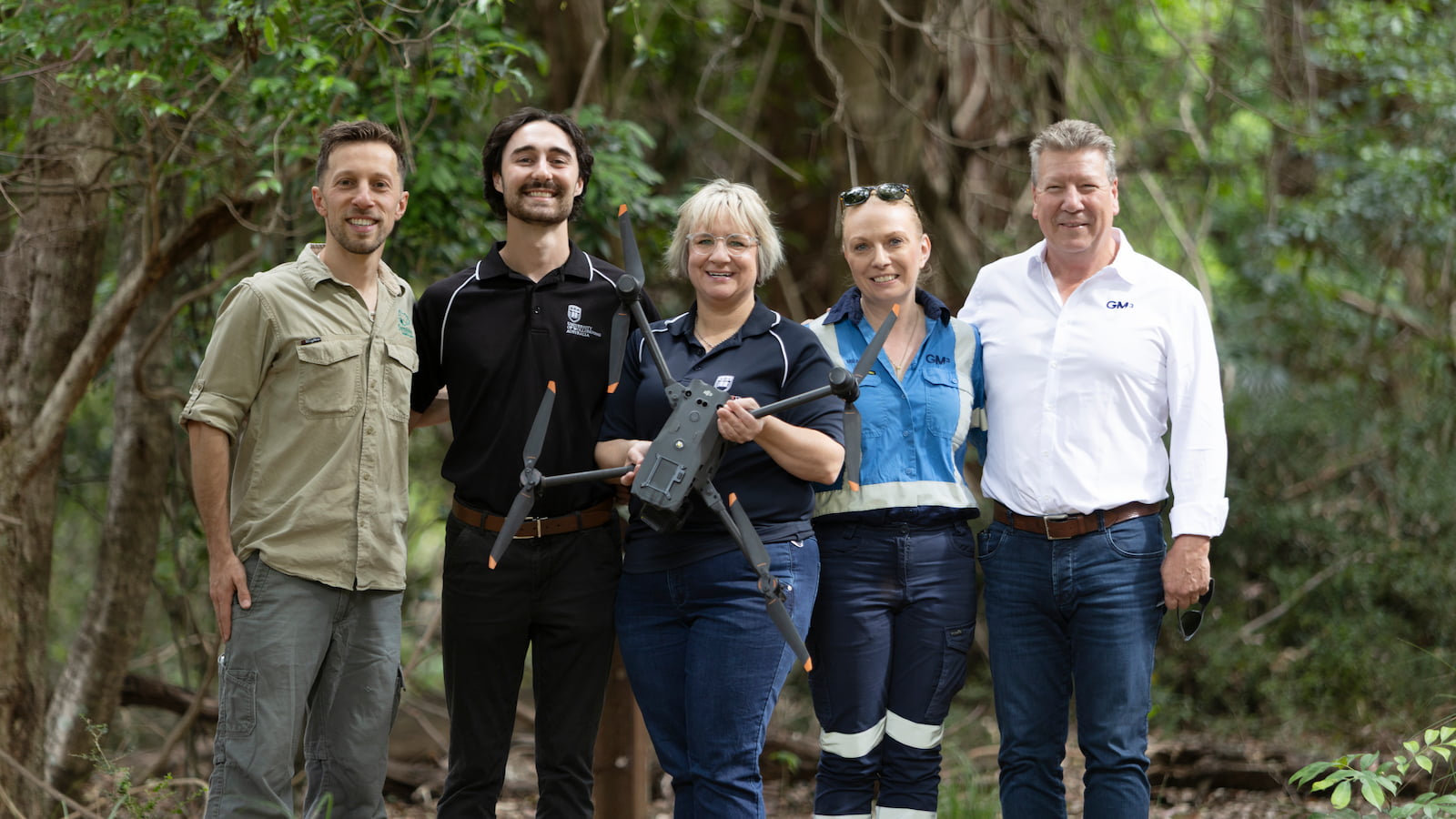 Five people stand in a row holding a drone in a rainforest setting. Photo: Symbio Wildlife Park
