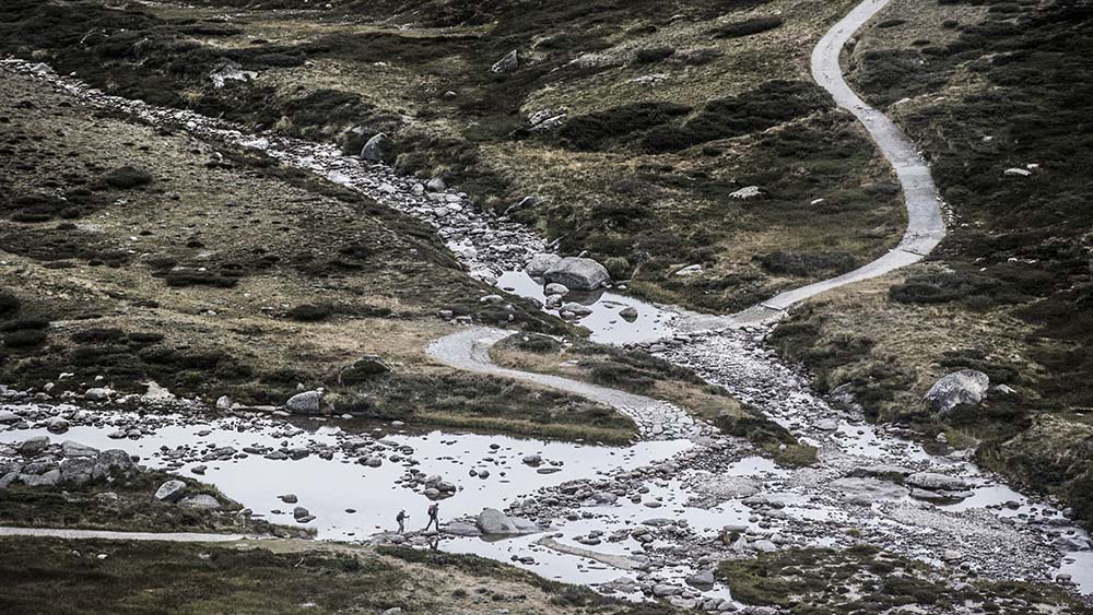 Hikers fording a creek in the Kosciusko National Park.