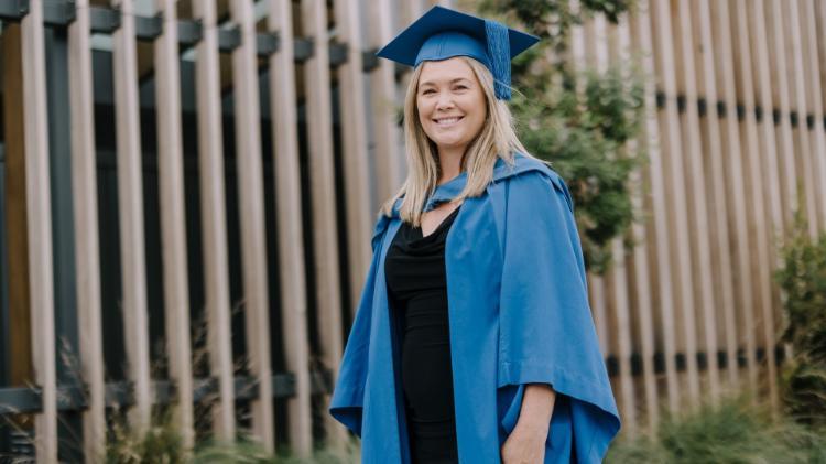 Nicole Pritchard wears a blue gown and cap and stands in front of the Batemans Bay Pavilions. Photo: Michael Gray