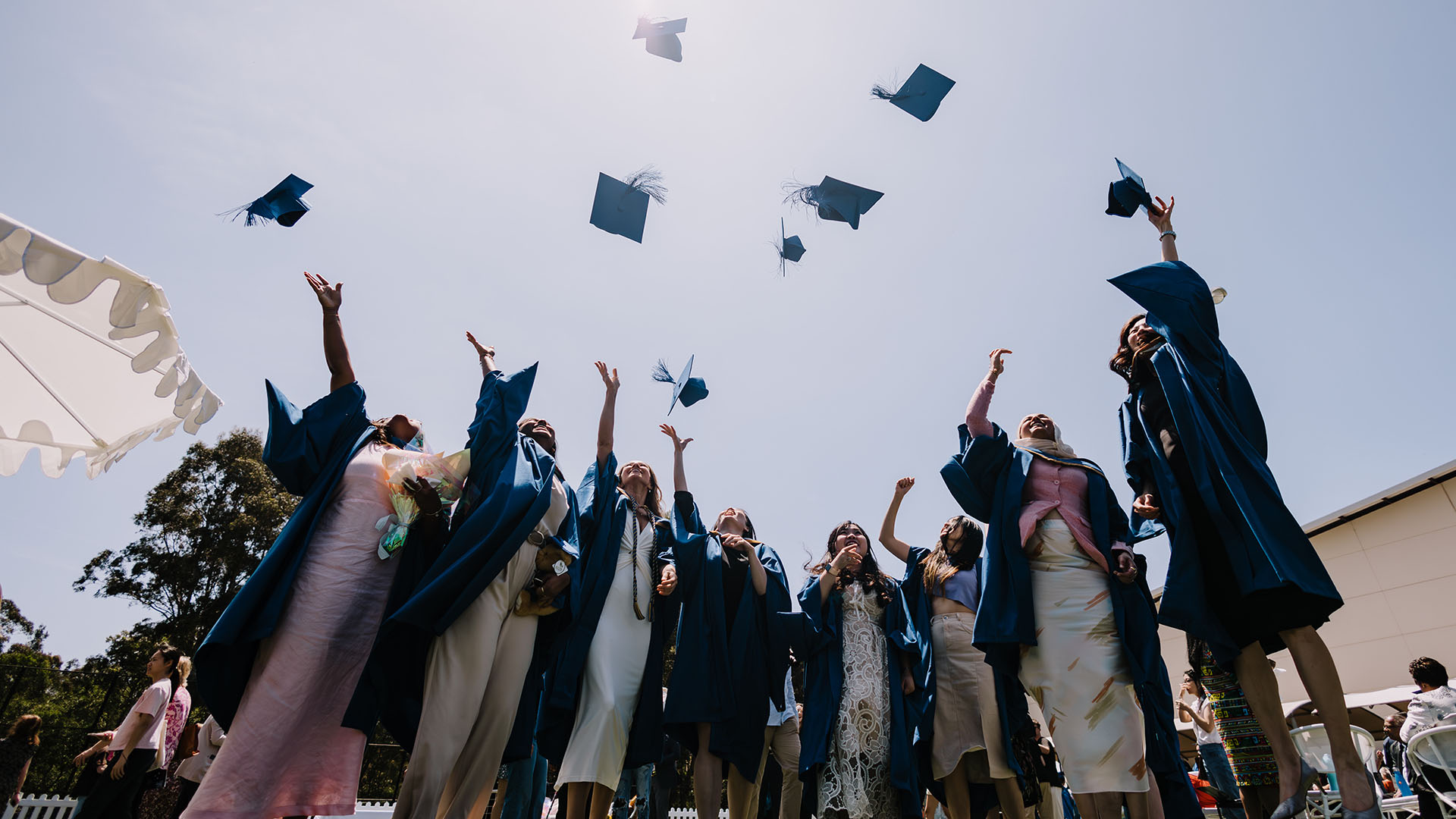 UOW graduates throw their mortarboards in the air after the completion of their graduation ceremony.