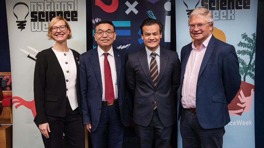 Four people, one female and three males, all smiling stand in a line in front of a Science Space backdrop. Photo: Michael Gray