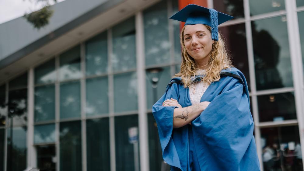 UOW graduate Molly Lasker wears a blue graduation gown and cap in front of Shoalhaven Entertainment Centre. Photo: Michael Gray