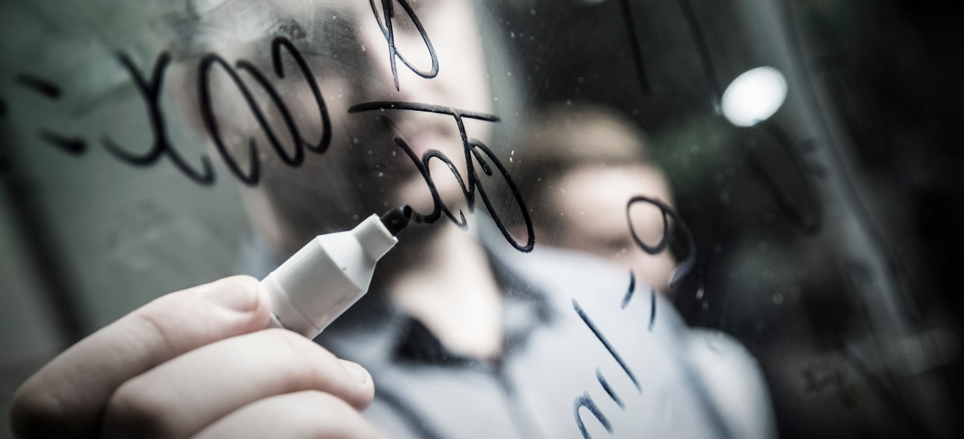 A photo of a man writing mathematics equations on a wall. Photo: Paul Jones