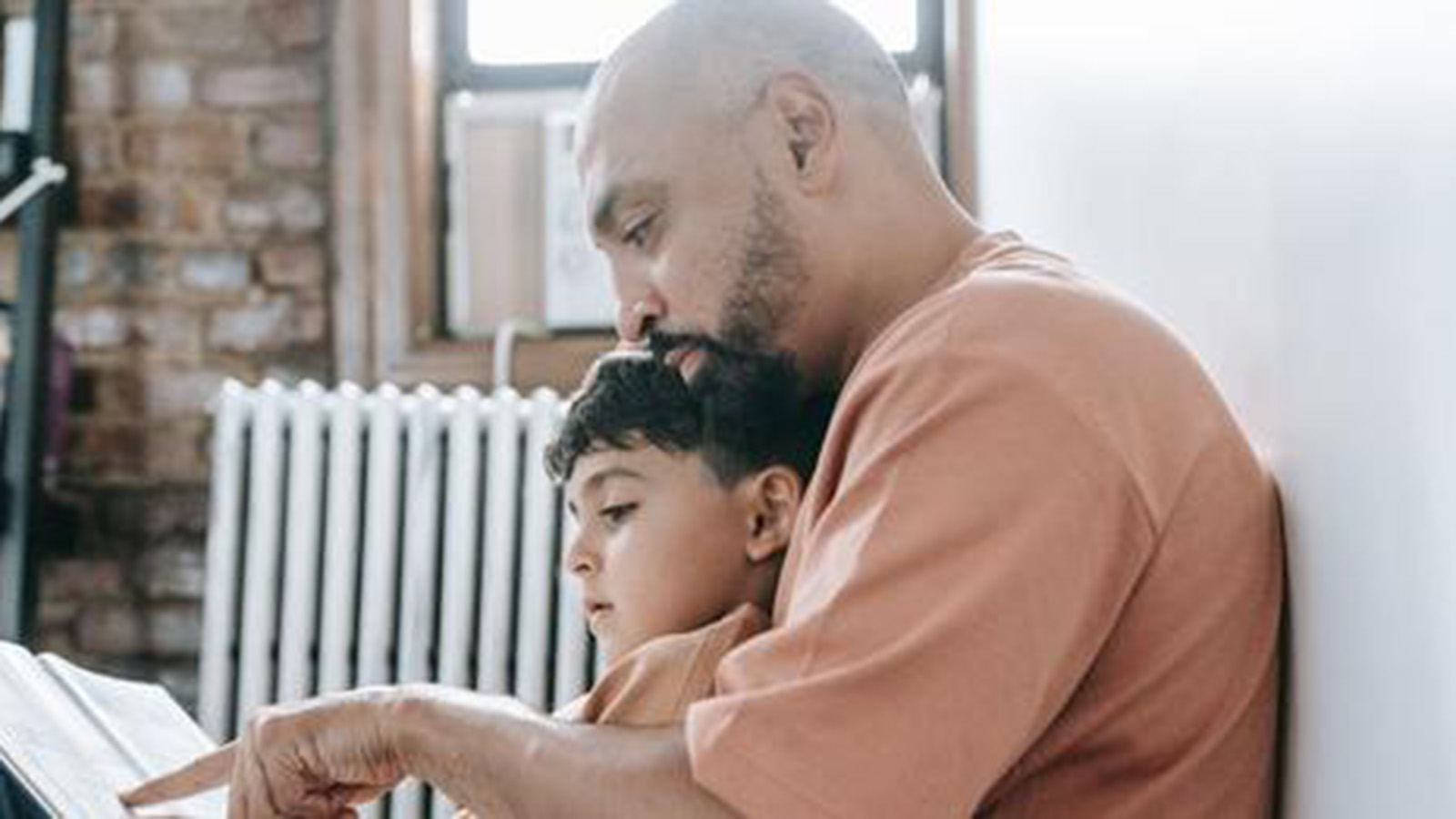 A man reads a book with his son.