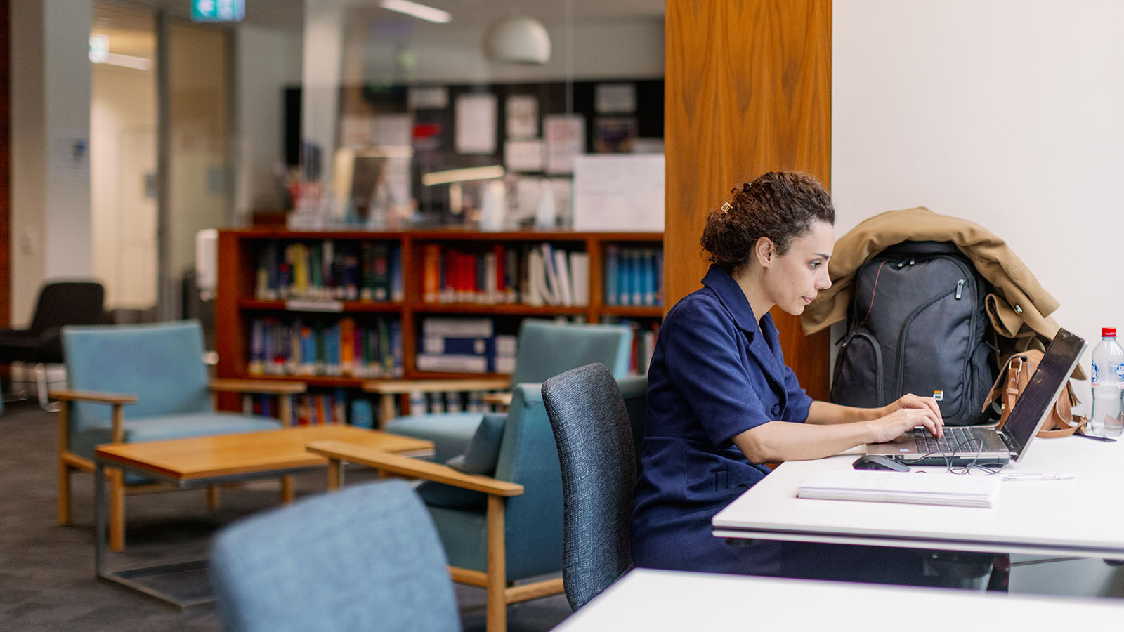 A female student works on her laptop in the library at Sydney Business School.