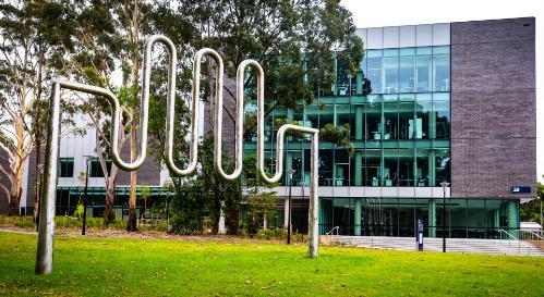 An image of a sculpture in the foreground, with the Jillian Broadbent Building in the background, on UOW