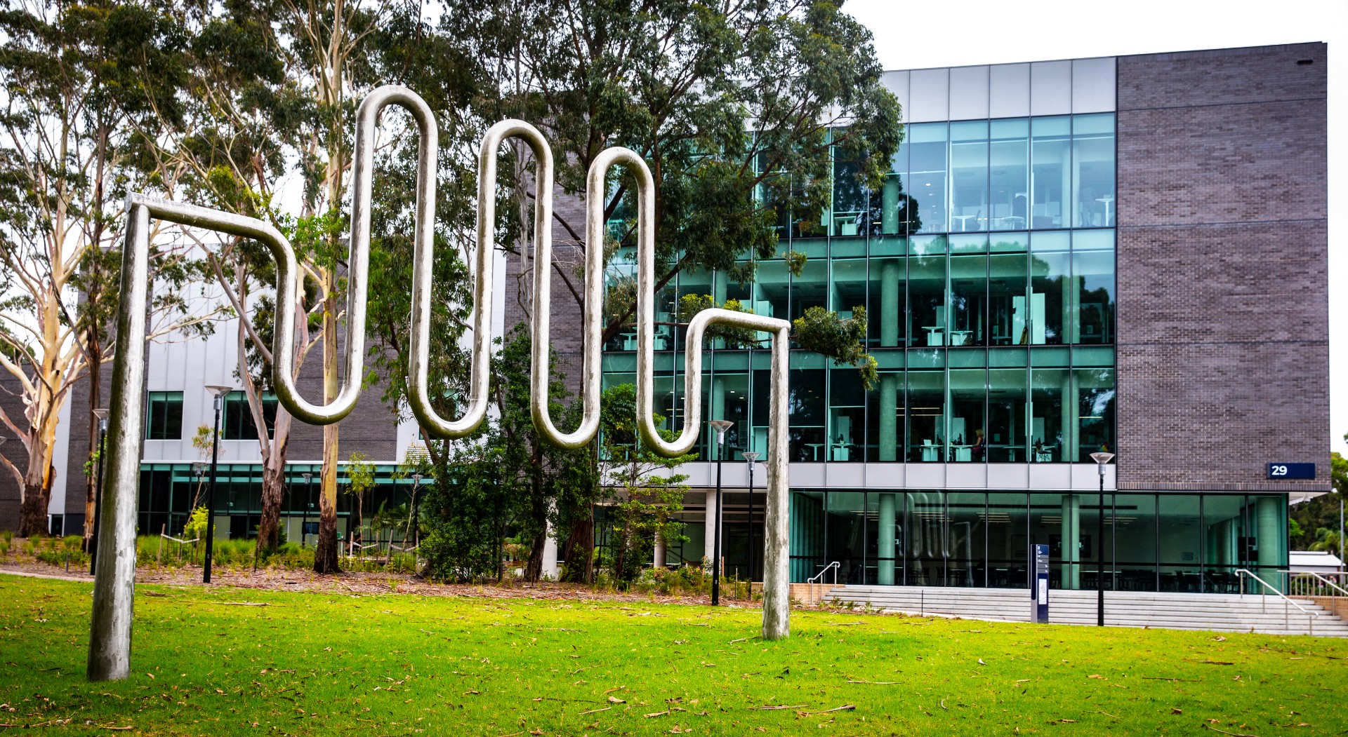 An image of a sculpture in the foreground, with the Jillian Broadbent Building in the background, on UOW