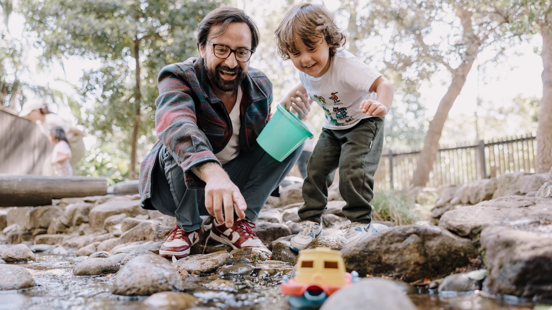 A father and son watch a boat float down a river in Early Start