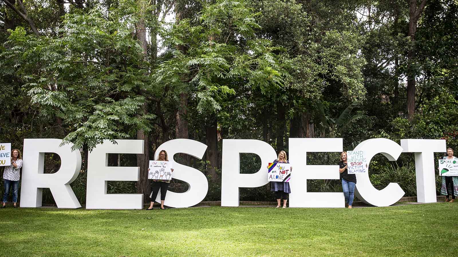 Members of the Safe and Respectful Communities team stand next to a large "Respect" sign