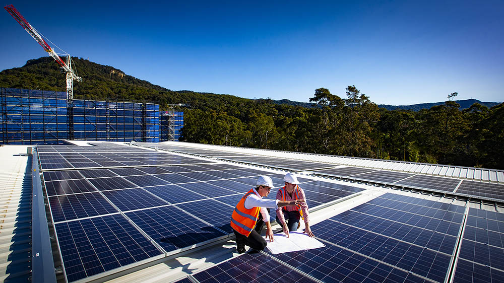 Engineers install solar panels on a building roof on the ý campus.