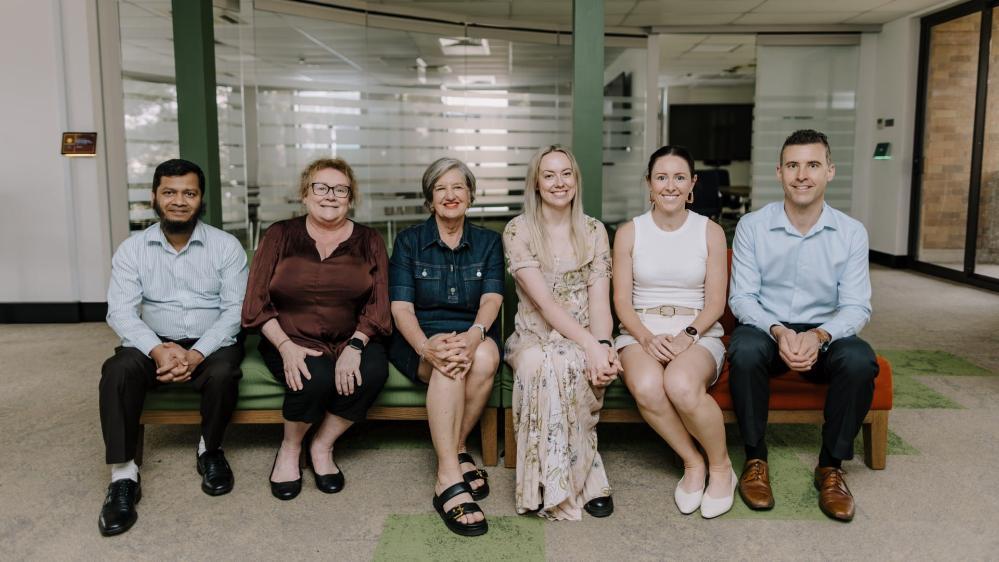 Dr Abdullah Al Mamun, Mrs Taryn McDonnell, Professor Lee Moerman, Dr Erin Twyford, Associate Professor Stephanie Perkiss, and Mr Scott Snaidero sit in a row on a bench. Photo: Michael Gray
