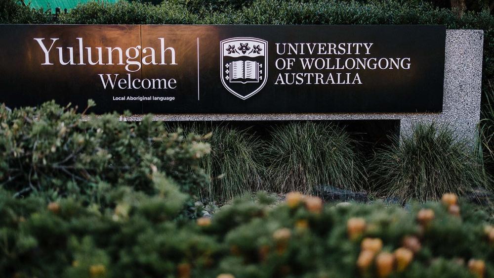 An entrance sign welcoming people to UOWs Wollongong campus in the local Aboriginal language.