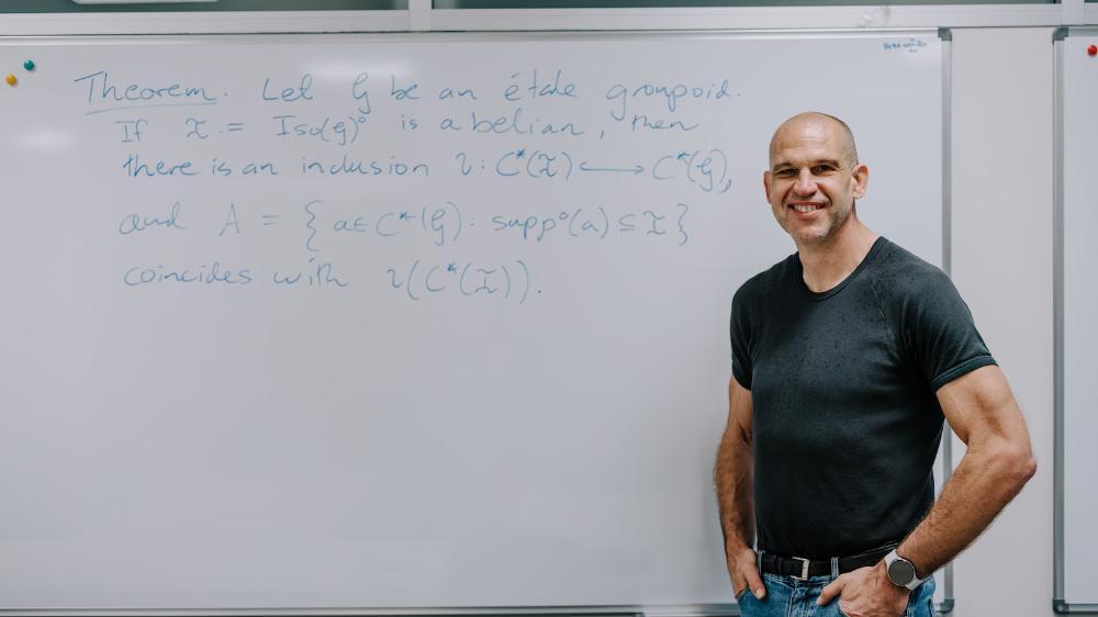 A man stands in front of a whiteboard with maths equations. Photo: Michael Gray