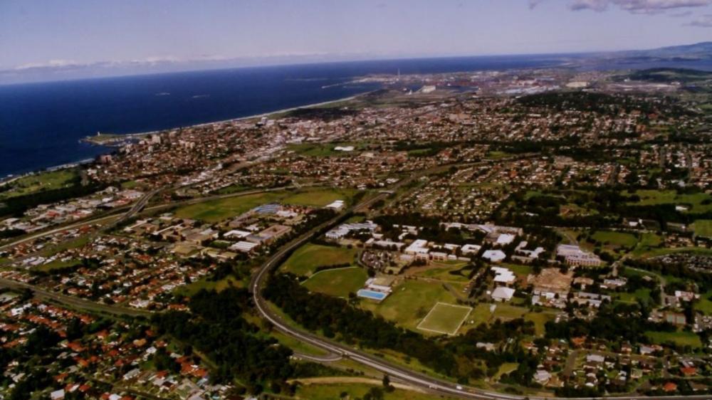An aerial shot of the University of Wollongong campus in the 1980s. The ocean is visible in the distance.