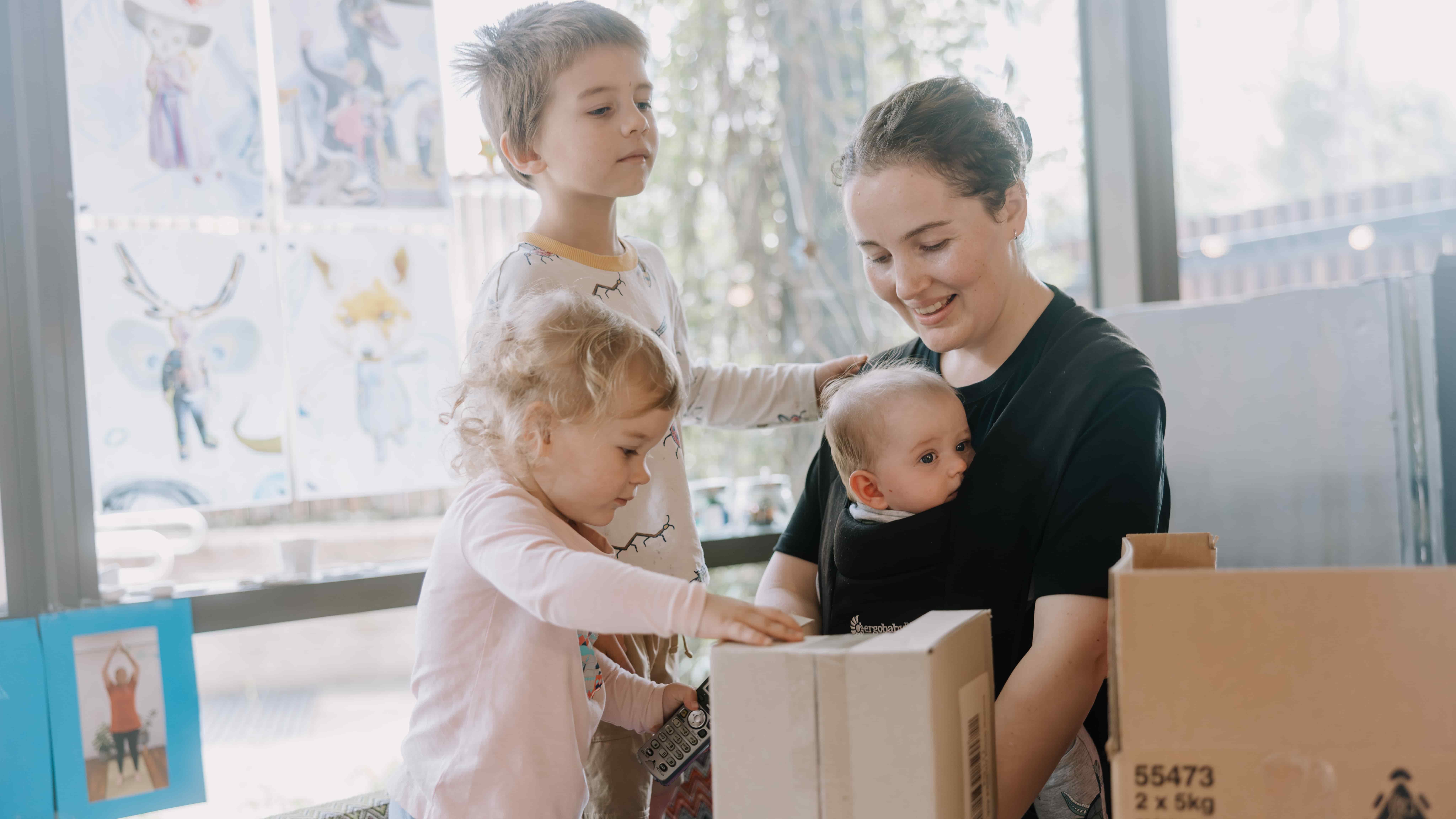 A mother wearing a baby carrier plays with two children at the Discovery Space. Photo: Michael Gray