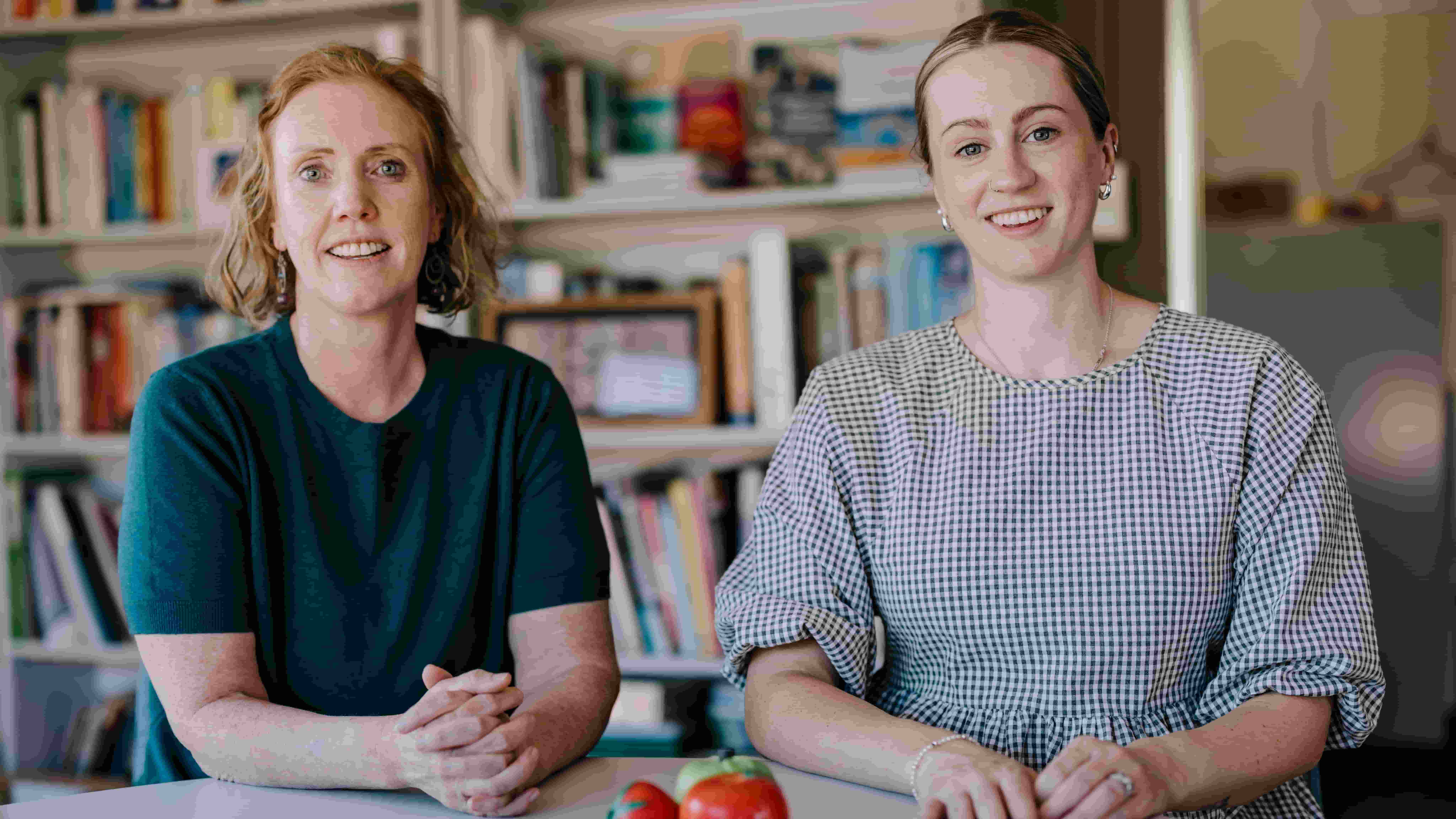 Kelly Lambert and Denelle Cosier sit at a table with a bunch of tomatoes in front of them. Photo: Michael Gray