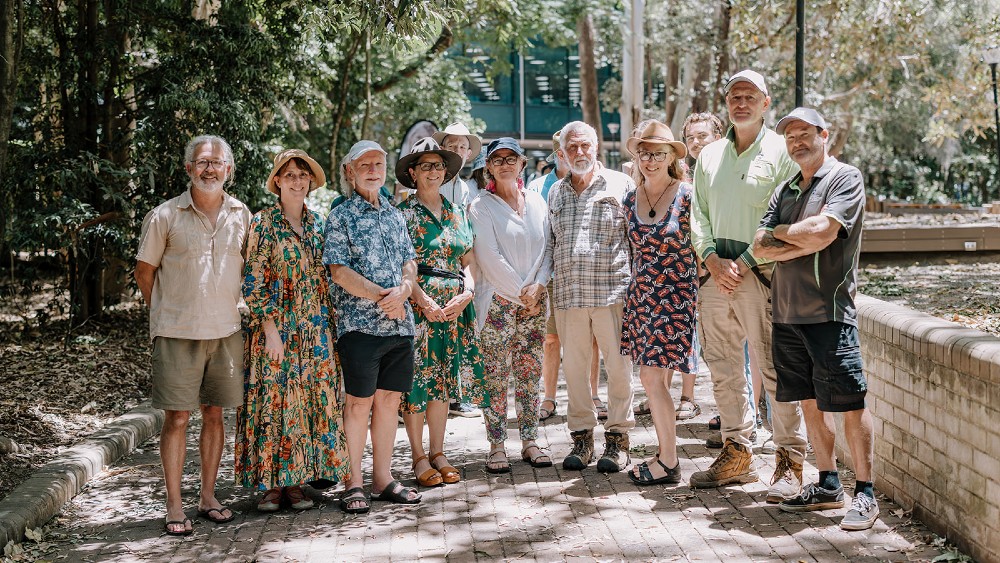 A group of 9 men and woman standing in a row together on a path