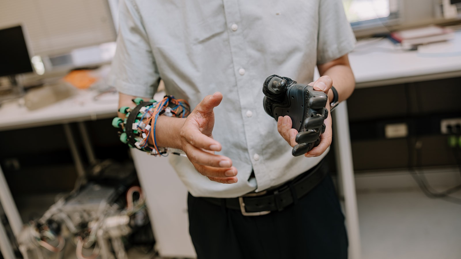 One arm and hand that has wiring attached to it and one prosthetic hand in a mirrored position