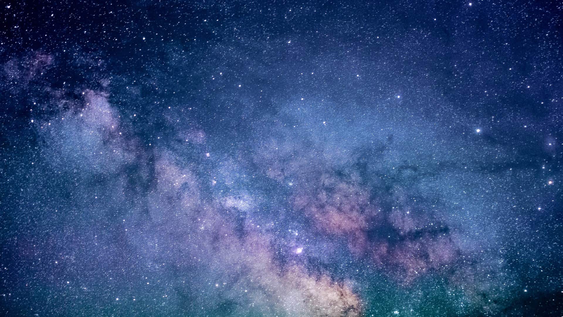 A colourful galaxy in blues, greens and purples is seen, with lots of sparkling stars. Photo: Jeremy Thomas/Unsplash