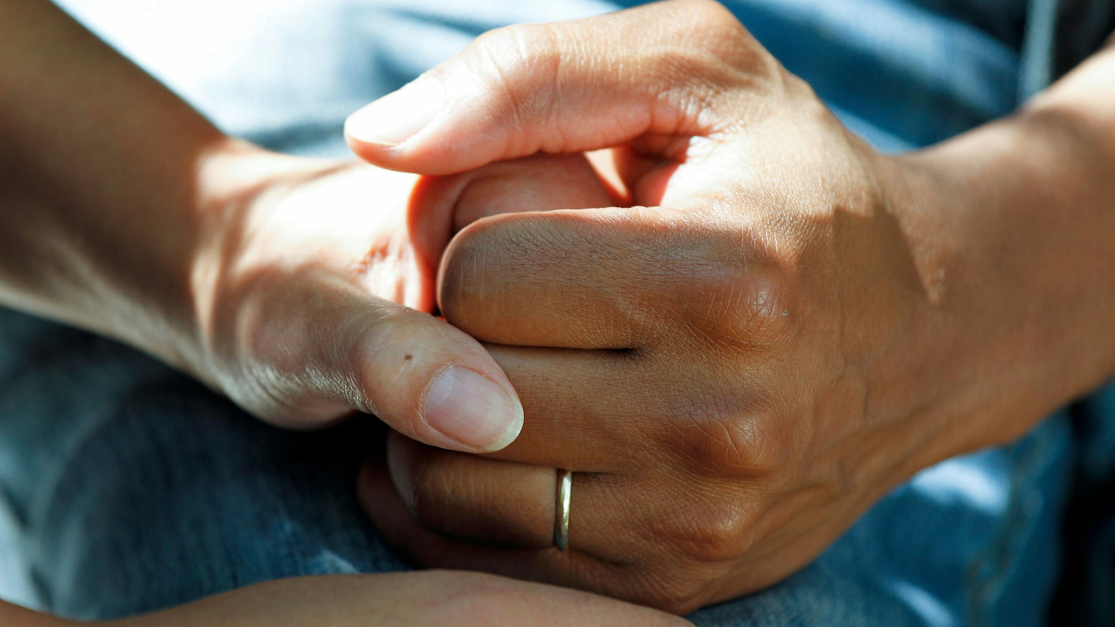 A close-up image of two hands clasped together in a hospital setting. Photo: National Cancer Institute/Unsplash