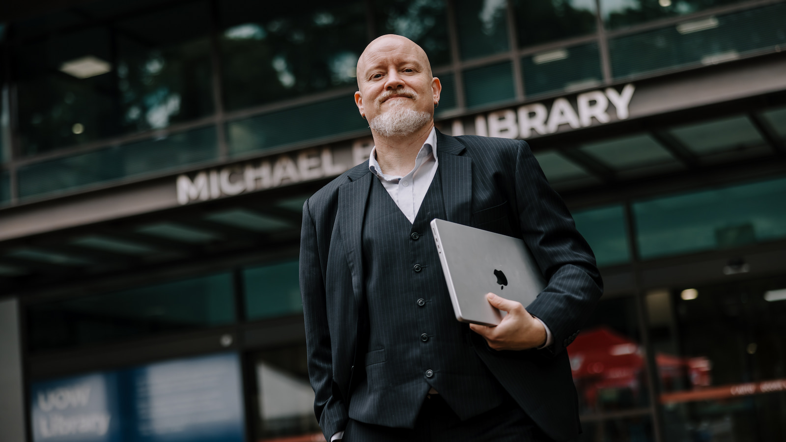 Brian Moore stands in front of the ÁñÁ«ÊÓÆµapp of ÁñÁ«ÊÓÆµapp Library holding a laptop computer. Photo: Michael Gray