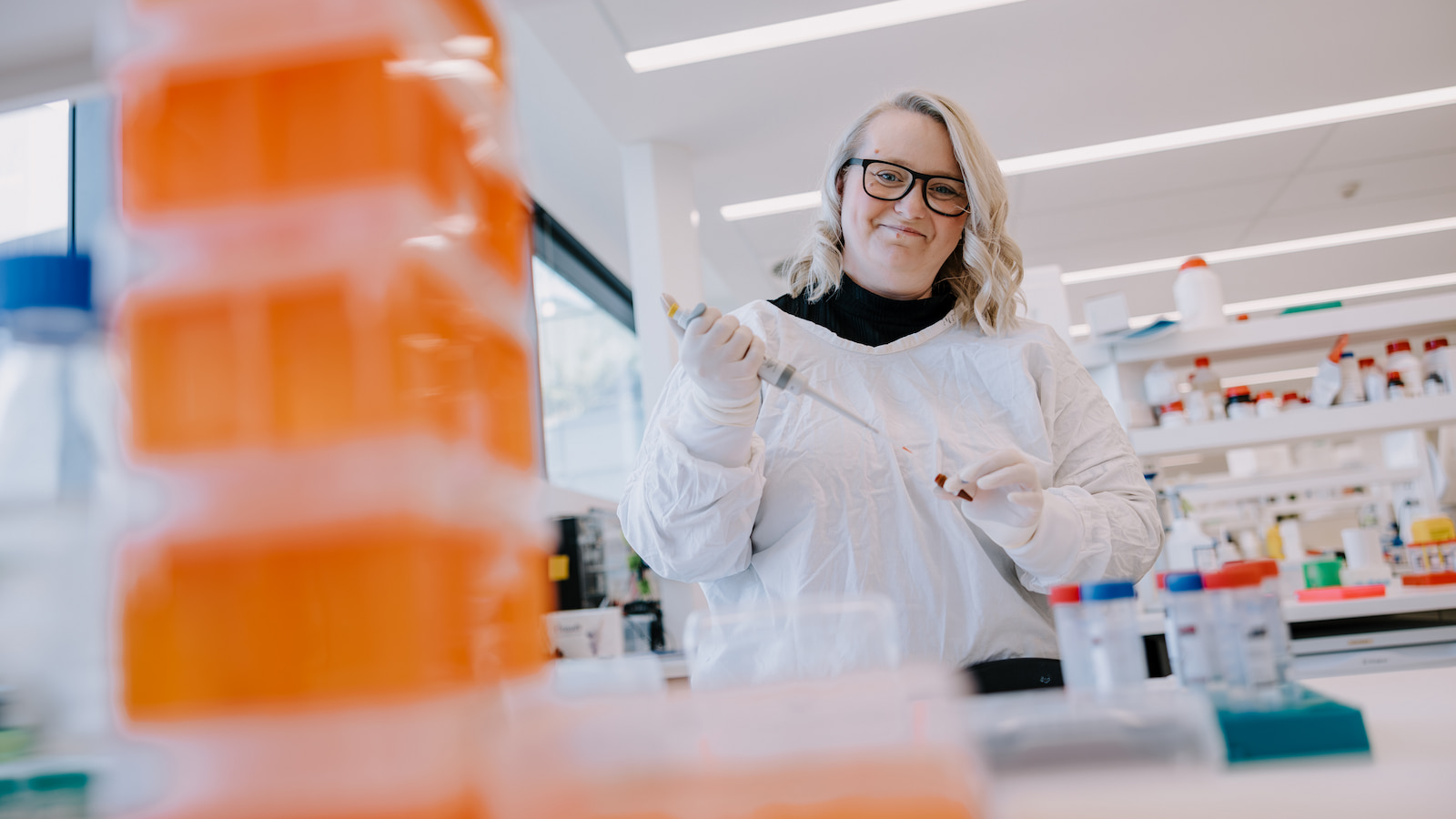 Dr Dezerae Cox, wearing a white lab coat, uses a test tube in a science laboratory. Photo: Michael Gray