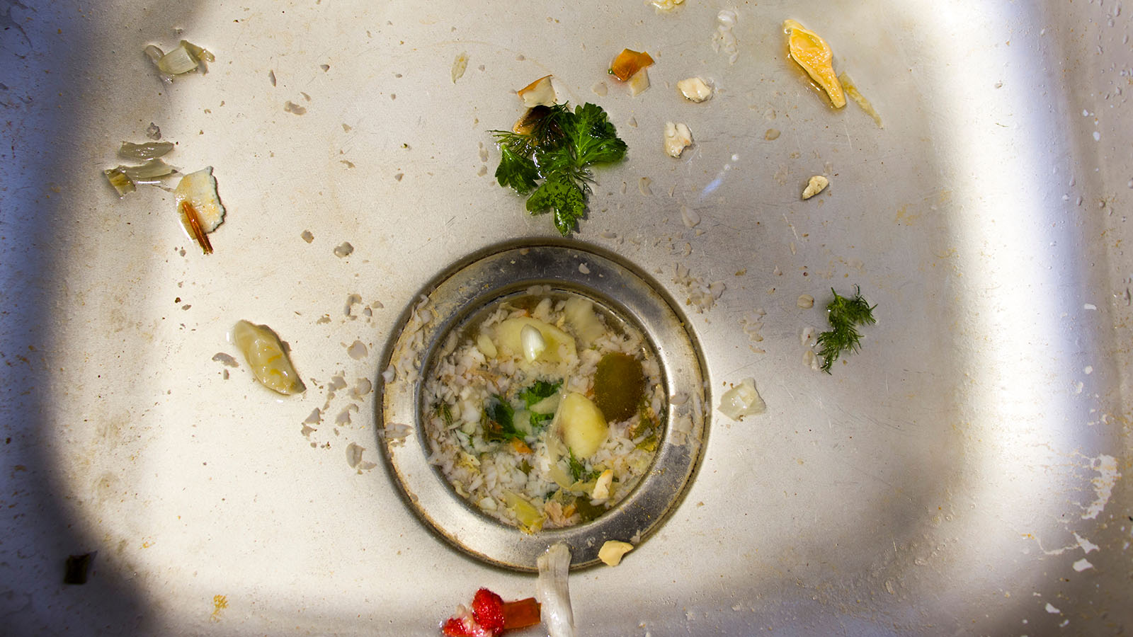 A top-down view of a kitchen sink clogged with food.