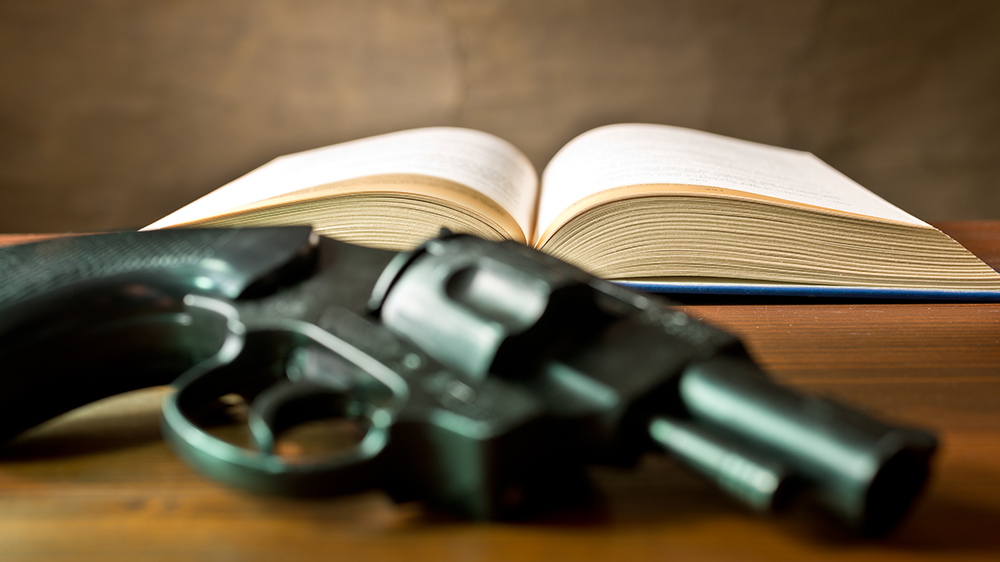 A gun lies next to an open book