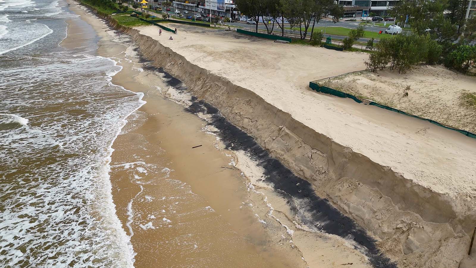 Drone shot showing significant beach erosion and sand cliffs near urban areas in Australia.