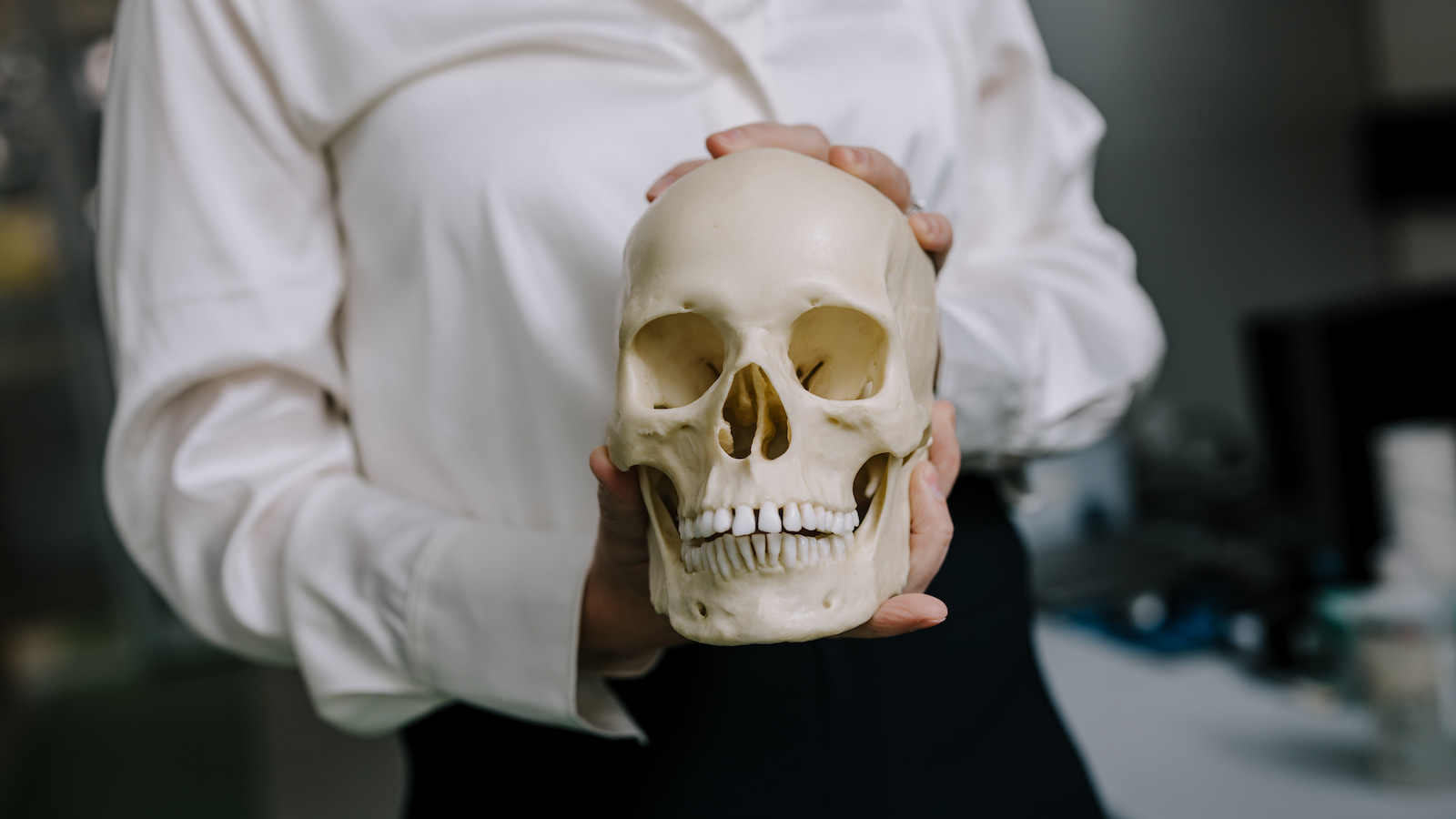 A woman holds a skull in front of her. Photo: Michael Gray
