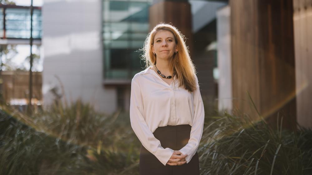 A woman stands in front of a building with the sun in the background. Photo: Michael Gray